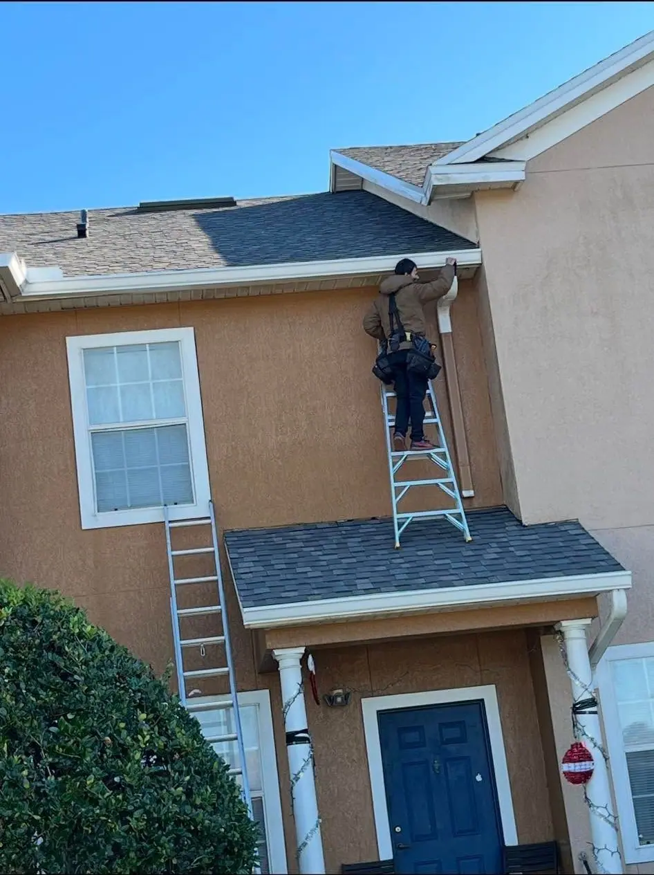 Crew member on a ladder at the gutter line of a two-story home