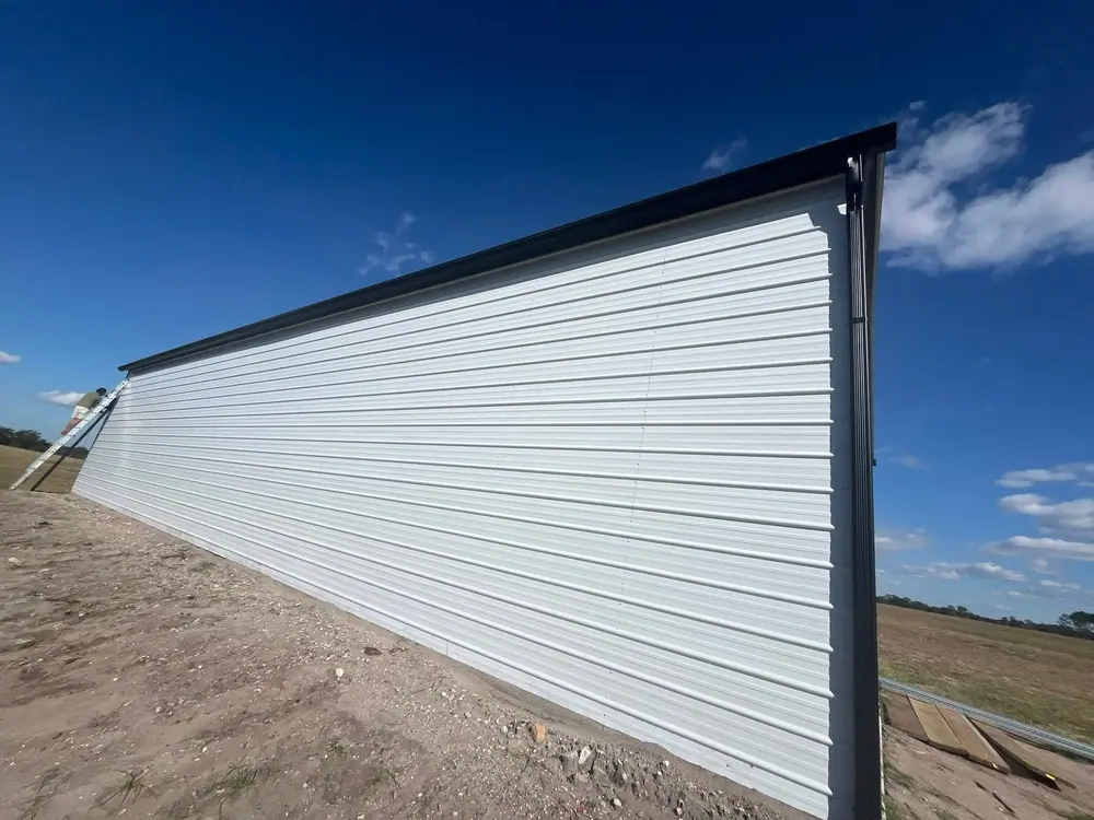 Long white steel building wall with a new gutter along the top edge