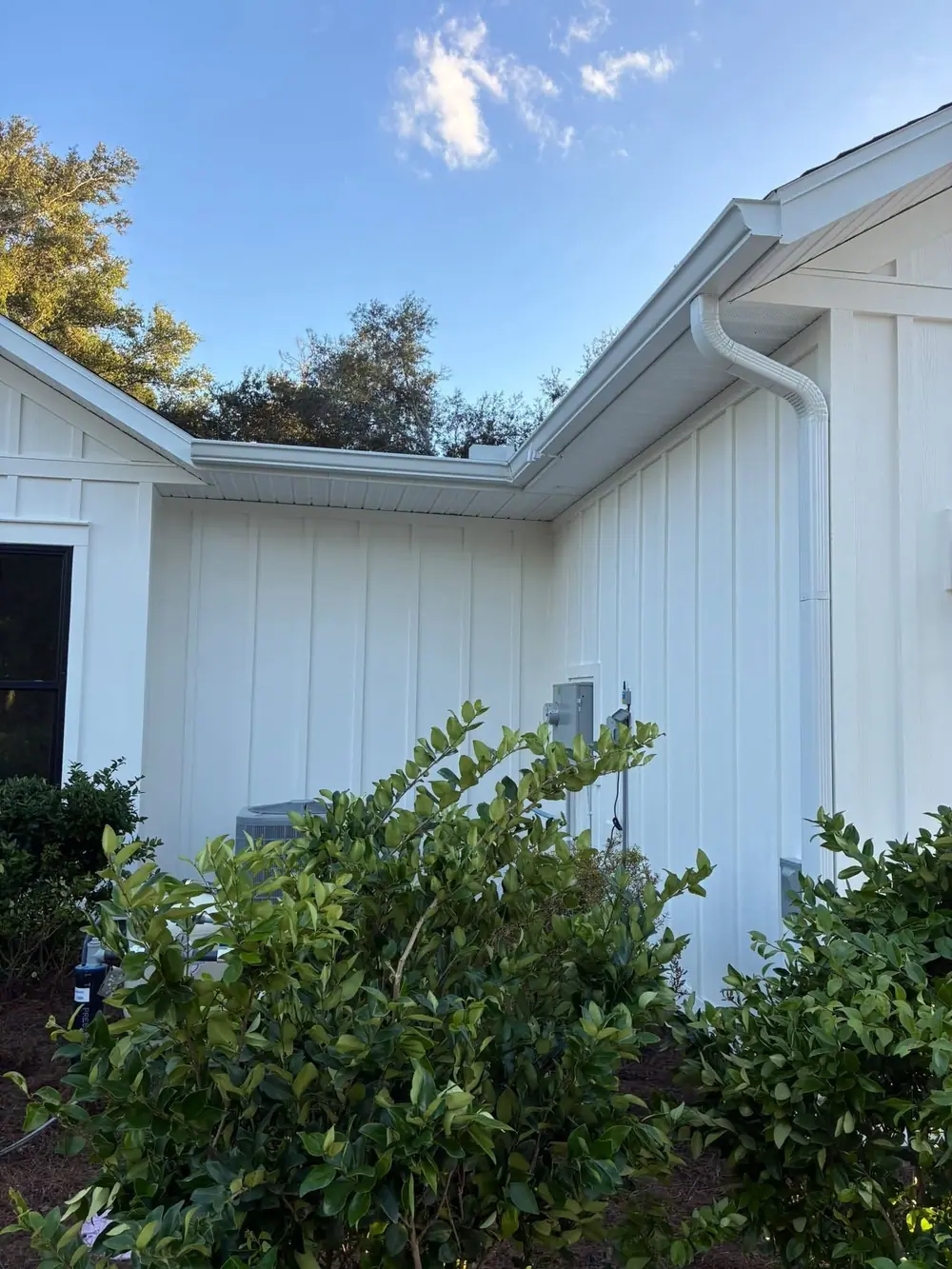White gutter and downspout on the corner of a board-and-batten home