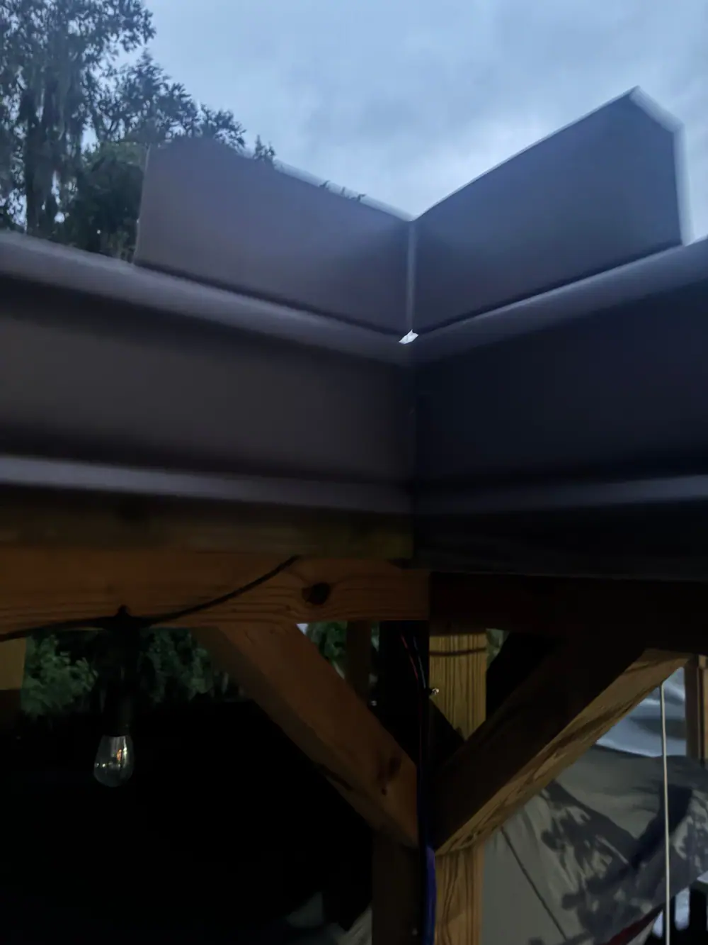 Dark bronze seamless gutter with a mitered corner on a backyard pavilion, Lake County FL