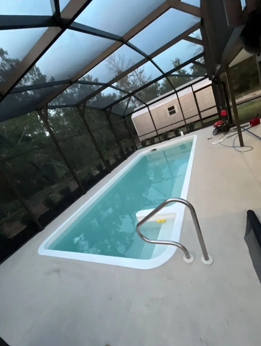 Pool screen enclosure after the work: clear blue water, clean white deck, fresh screen