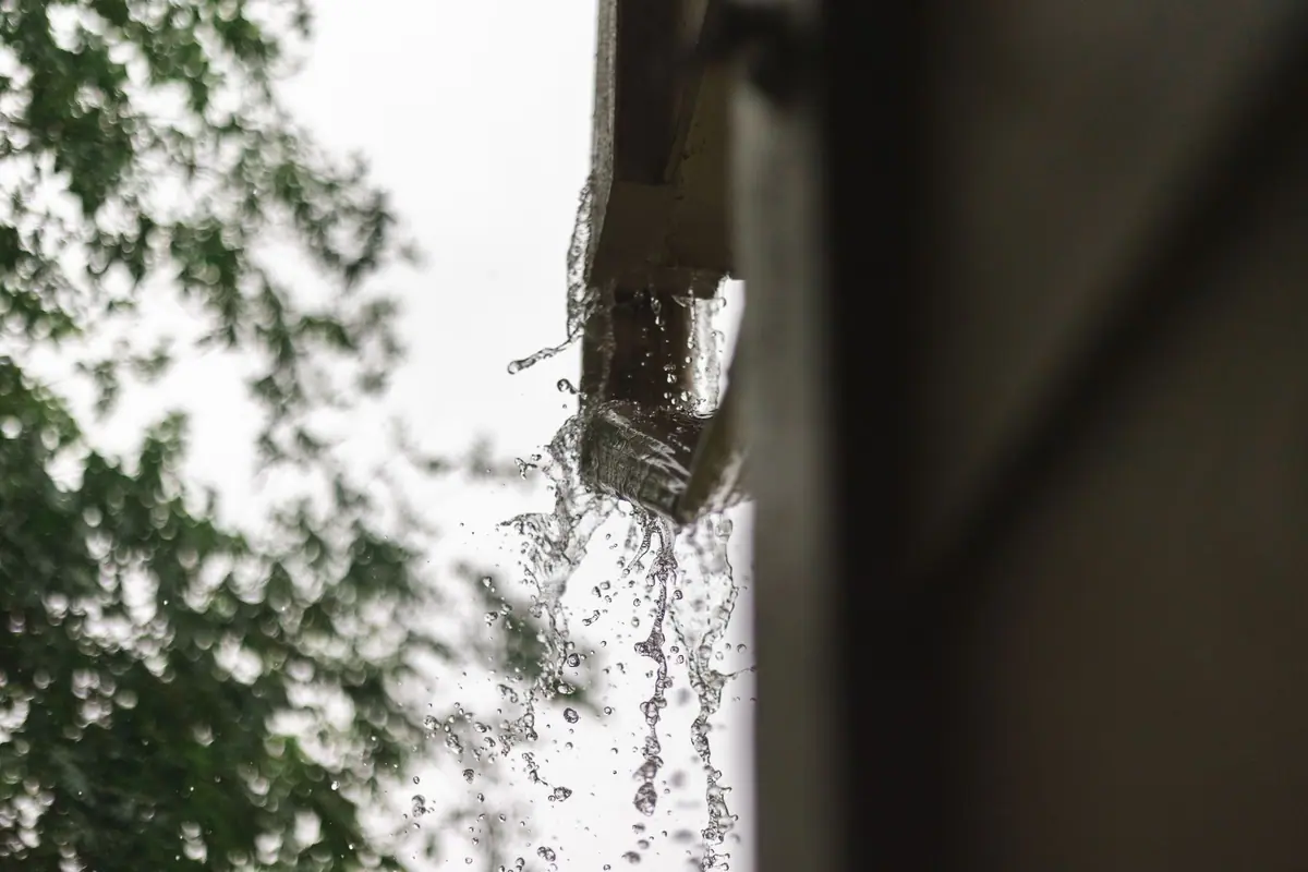 Rain pouring out of a downspout and off an eave in a heavy storm (stock photo)