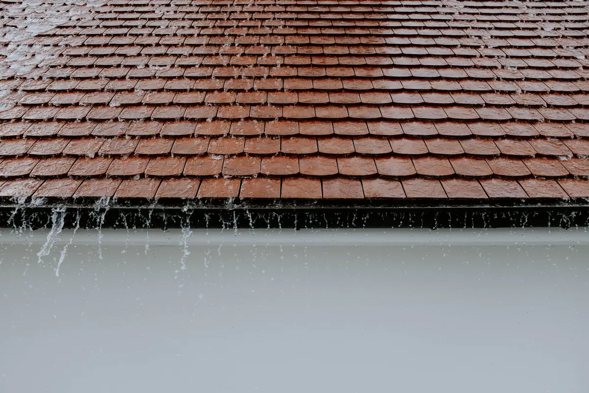Rain running off roof tiles into a white gutter (stock photo)