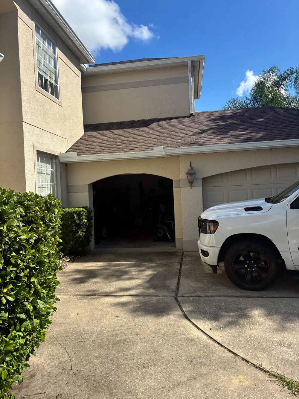 Two-story stucco home with white gutters over the garage and a shingle roof