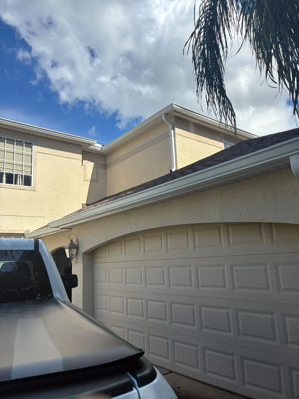 Two-story stucco home with white gutters and downspouts on every roofline