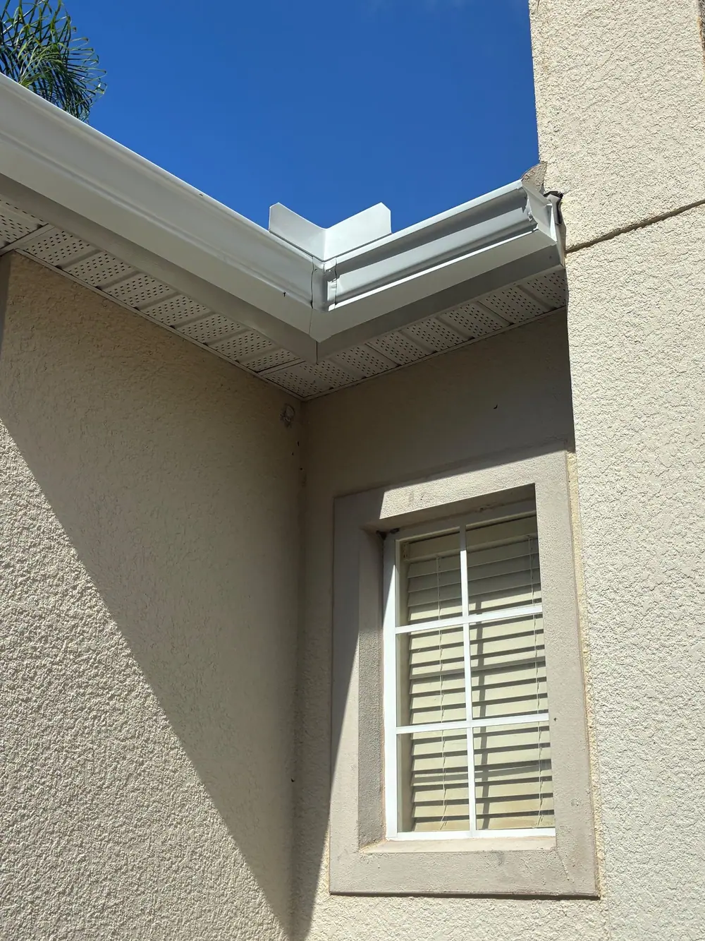 White seamless gutter with a mitered inside corner on a stucco home